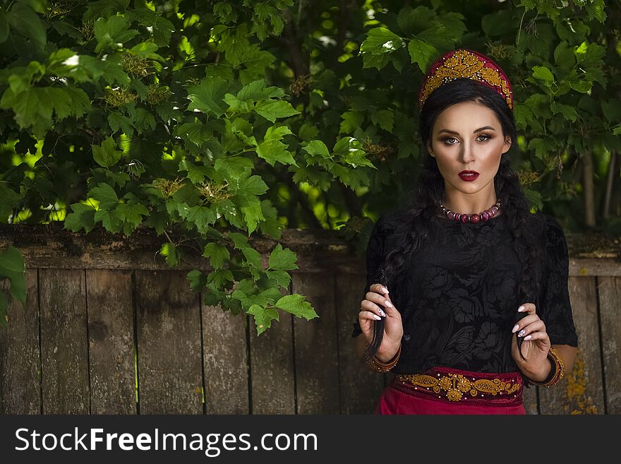 Glamour Fashion Model in Russian Style Decorated Kokoshnik Posing Outdoors Against Old Wooden Fence