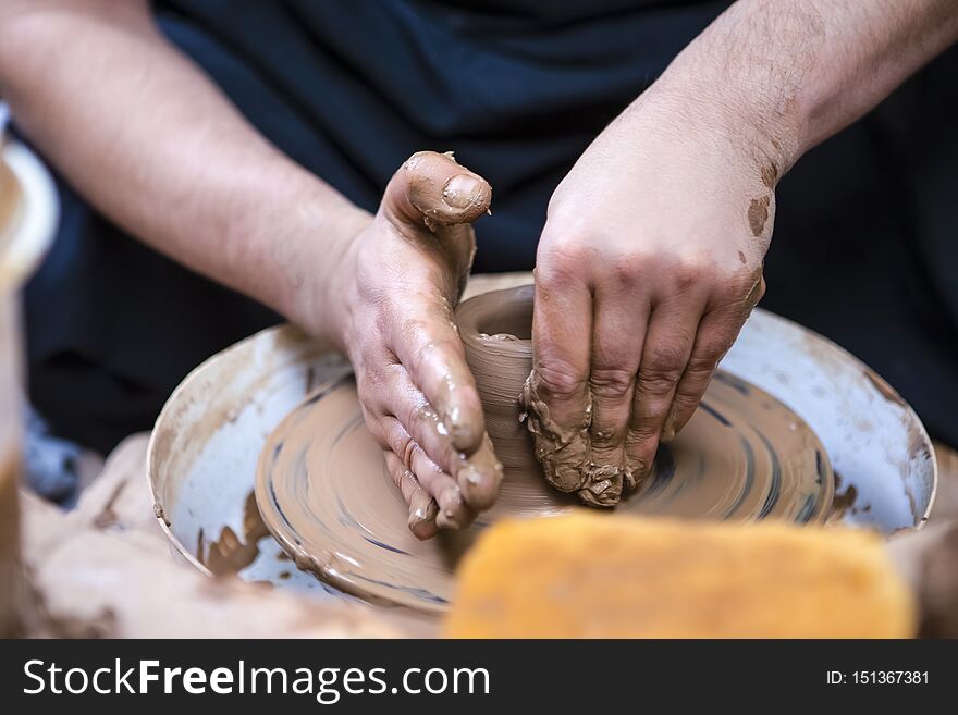 Closeup of Hands of Male Potter Working with Clay Lump on Potter`s Wheel in Workshop