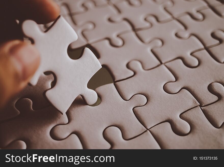 Last piece of white plain jigsaw holding by hand, step of success concept, dramatic