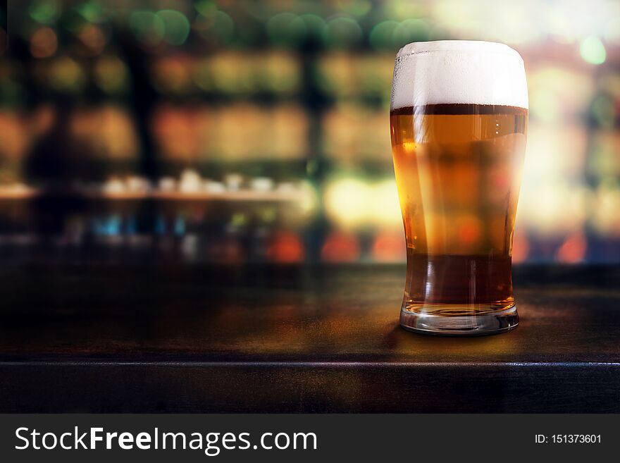 Glass of Beer on Table in Bar or Restaurant. Side View. Night Scene