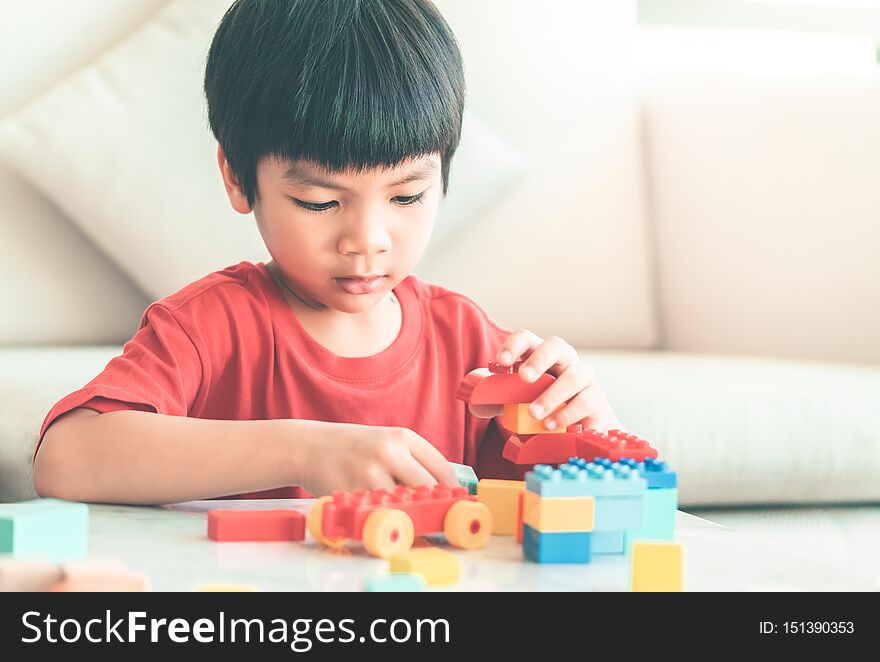 Boy stacking Toy blocks on a living room table