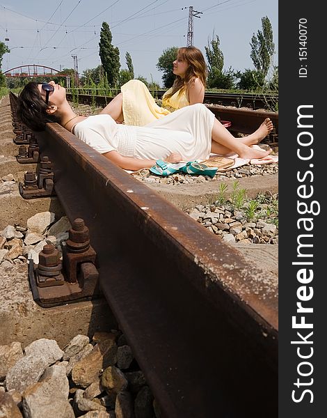 Young girls laying on the railroad in the middle of a bright day. Young girls laying on the railroad in the middle of a bright day