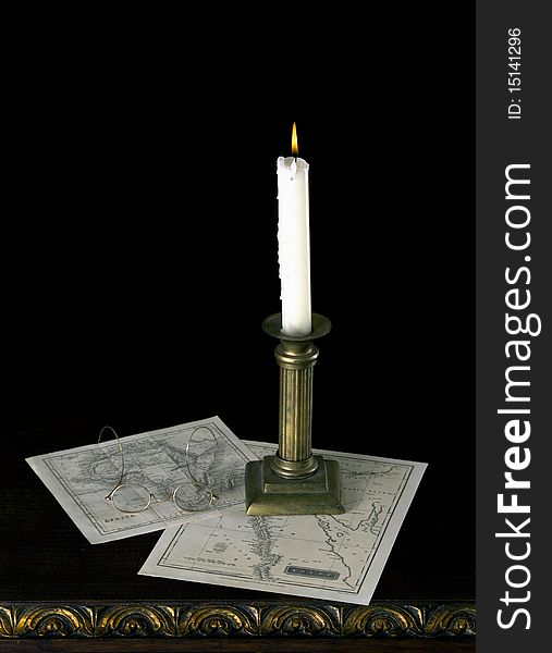 A candle with old maps  in old candlestick on old