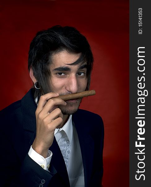 Portrait of young man with cigar on red background