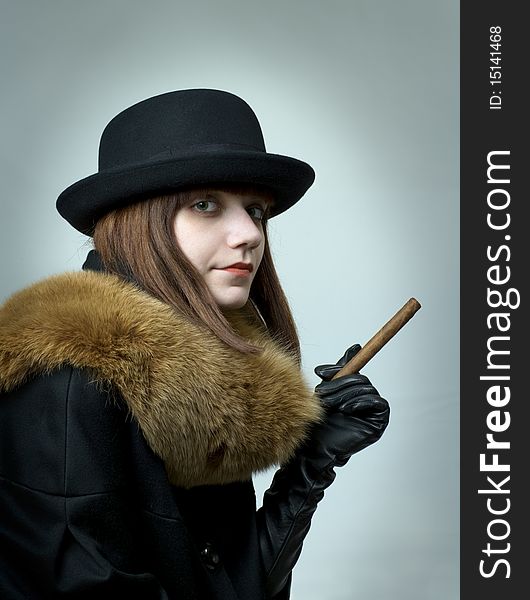 Portrait of young woman with cigar on  gray background