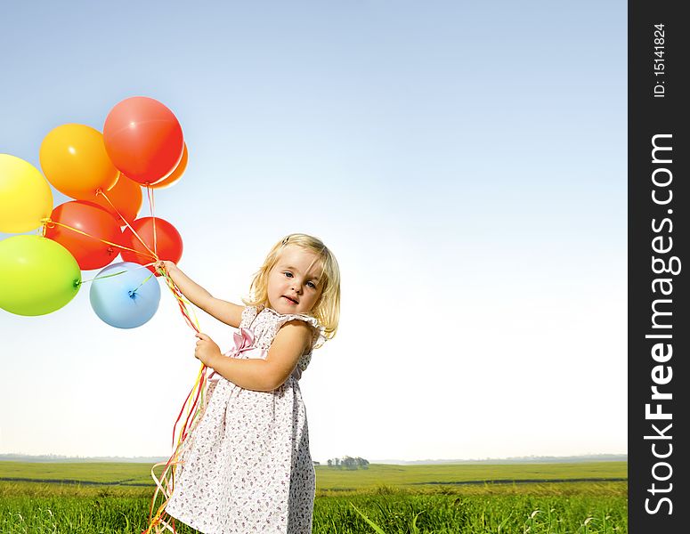 Adorable young girl holds tightly to a large bunch of helium filled balloons. Adorable young girl holds tightly to a large bunch of helium filled balloons