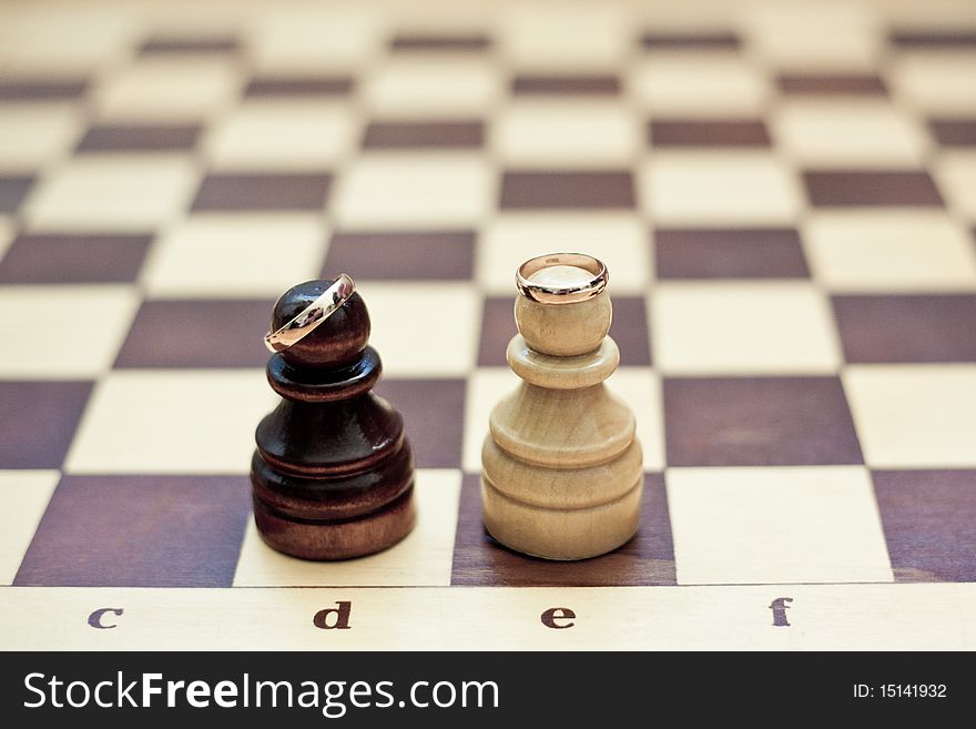 Gold wedding rings on chess figures