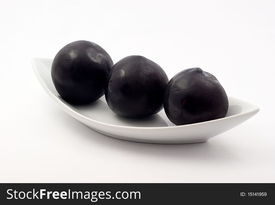 Fresh ripe plum on a plate on a white background