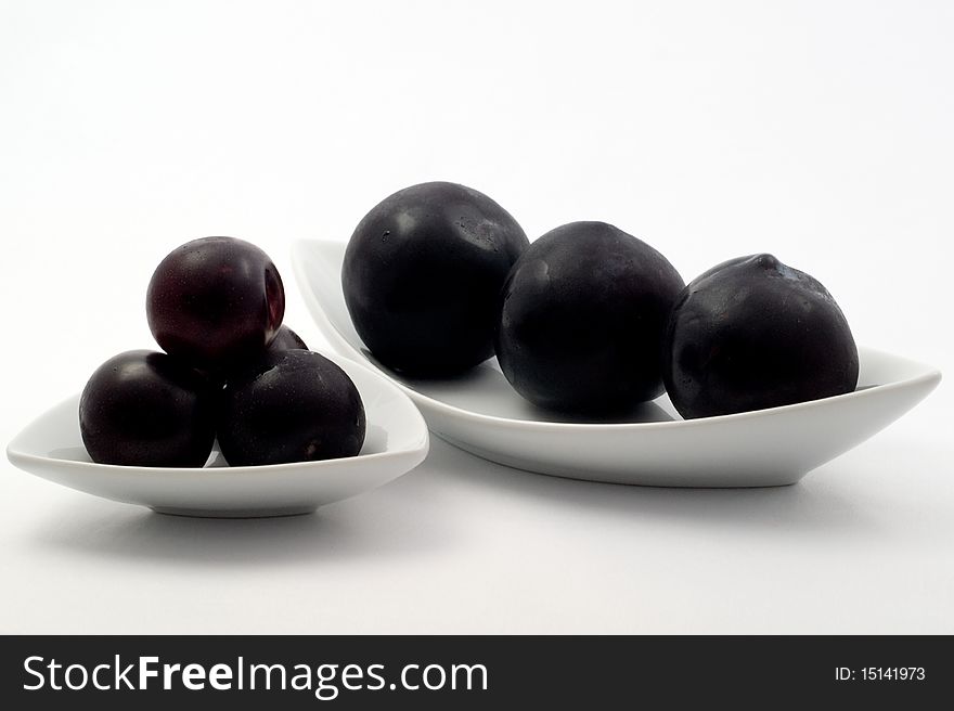 Fresh ripe plum on a plate on a white background