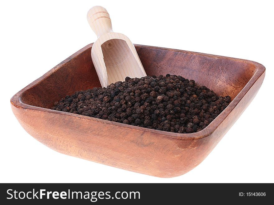 Black pepper - spice in a plate with a measured wooden spoon.