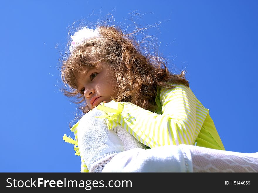 The thoughtful girl sits having leant on a knee against the sky. The thoughtful girl sits having leant on a knee against the sky