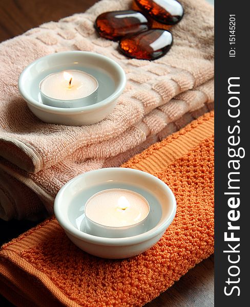 Spa candles on towels and decorative stoness
