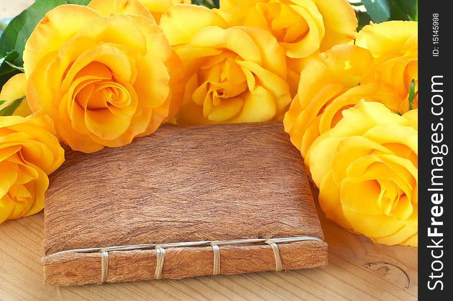 Bouquet of yellow roses on a book with a textured handmade cover