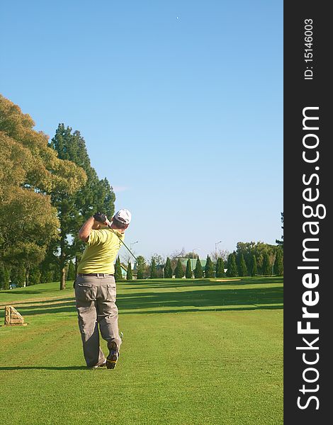 Young male golfer hitting the ball from the fairway on a beautiful summer day. Young male golfer hitting the ball from the fairway on a beautiful summer day