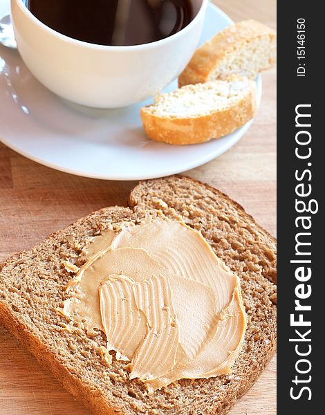 Two slices of Tasty healthy wholewheat bread with peanut butter spread and cup of black coffee on the table. Two slices of Tasty healthy wholewheat bread with peanut butter spread and cup of black coffee on the table