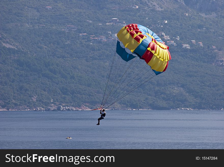 A man flying on a parachute over the bay near the town of Budva, Montenegro. A man flying on a parachute over the bay near the town of Budva, Montenegro