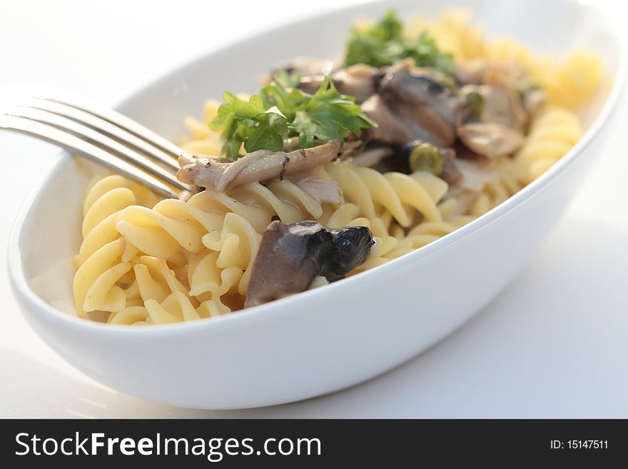 Fricassee with pasta in a white bowl with fork