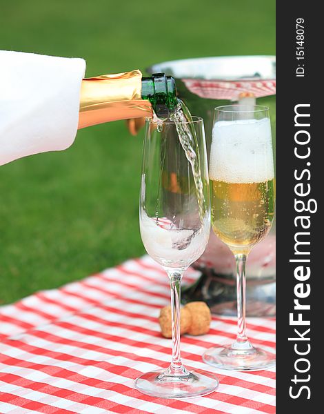 Champagne being poured to glasses at a summer picnic. Champagne being poured to glasses at a summer picnic