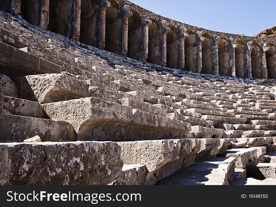 Stone benches and part of stone gallery in ruins of an ancient amphitheater in the disappeared city Aspendos, Turkey