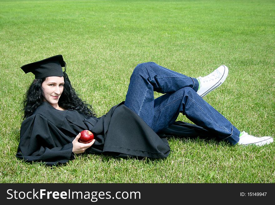Young caucasian student laying on the grass with apple
