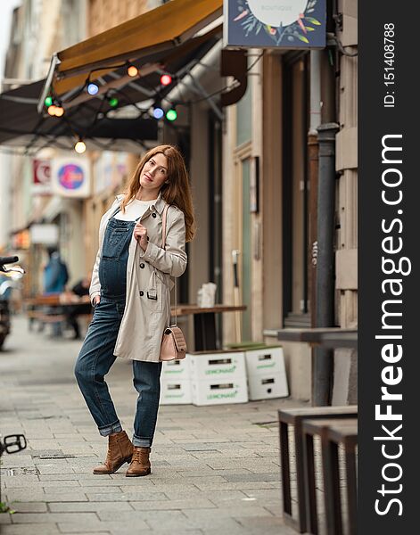 Beautiful Young Pregnant Woman Wearing Casual Clothes Walking Through The City Streets. Concept Of Motherhood And Pregnancy.