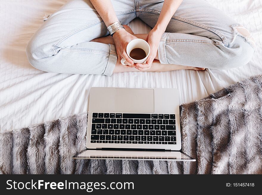 Unrecognized woman drinking coffee and watching a Tv series on her laptop