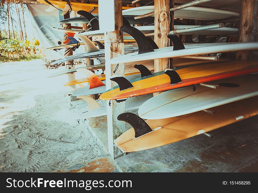 Set of different colorful surf boards in a stack available for rent on the beach. vintage color tone effect