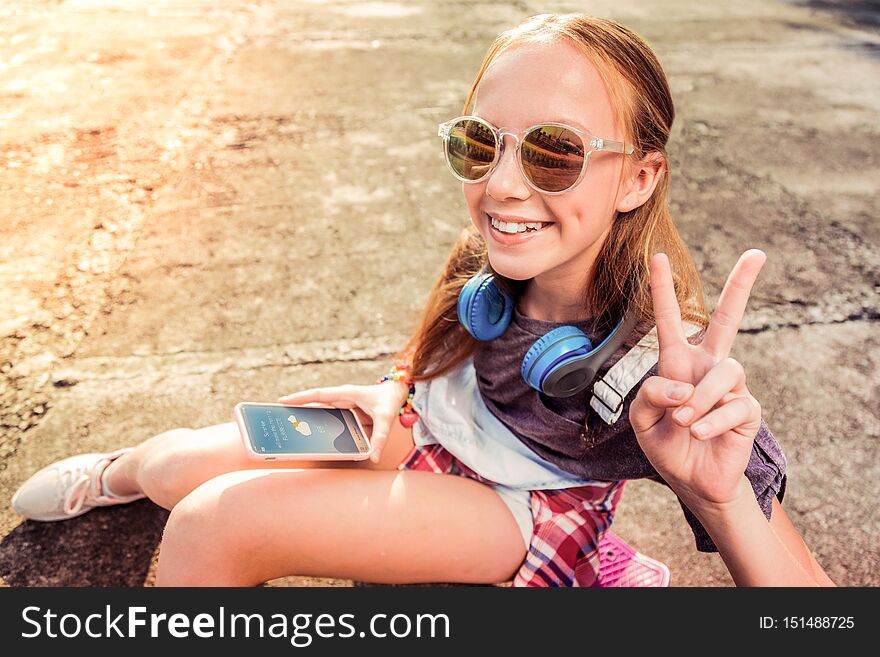 Being in great mood. Pretty little girl with wide smile wearing dark sunglasses while showing her mood during hot summer day