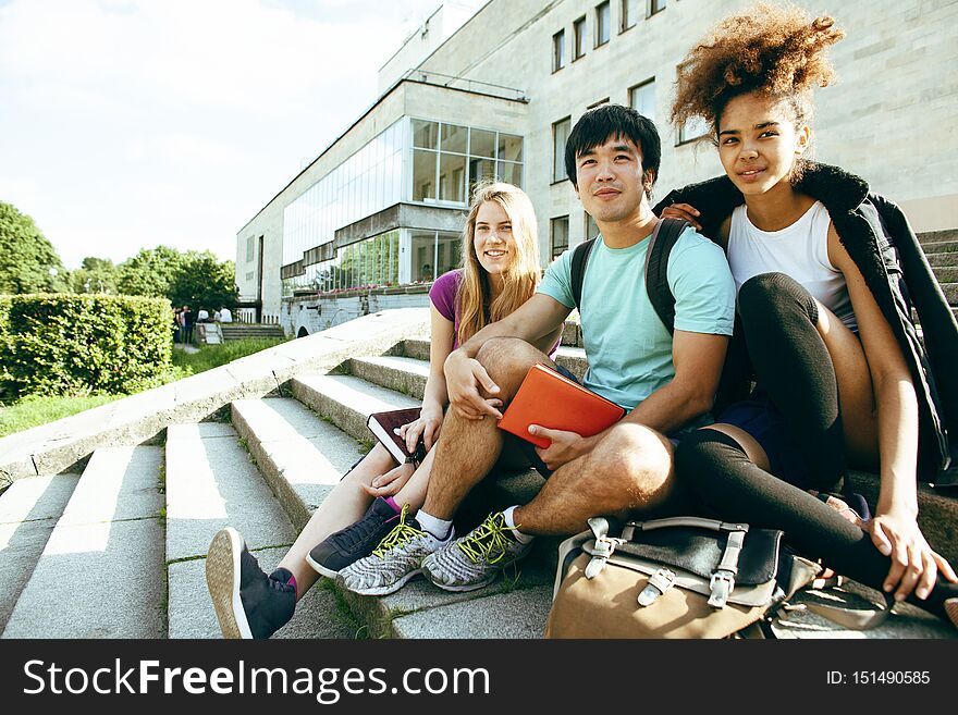 Cute group of teenages at the building of university with books huggings, diversity nations students lifestyle