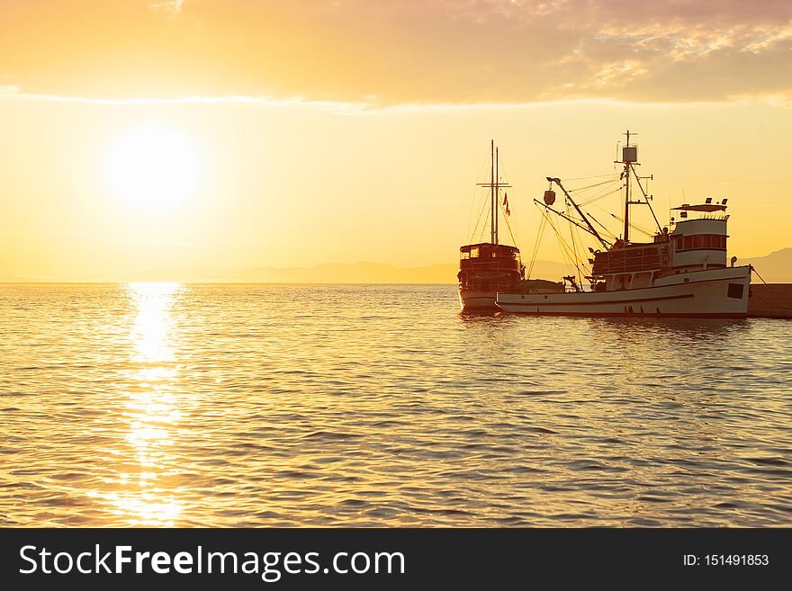Fishing trawler at sunrise moored in the beautiful harbor of a small town Postira - Croatia, island Brac