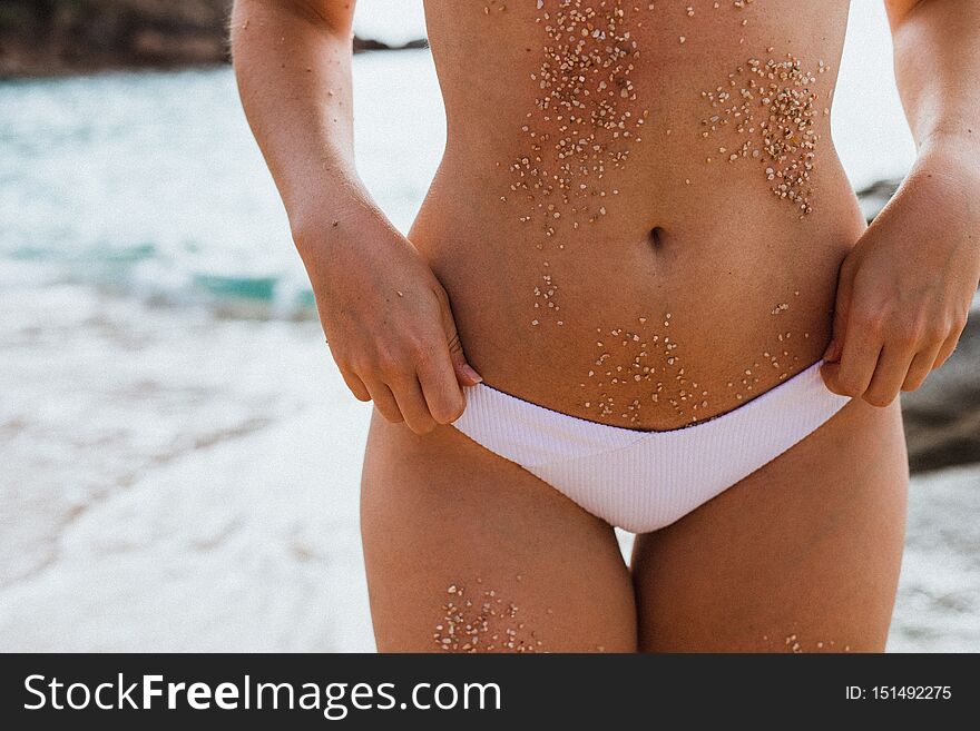 Women body in white bikini with sand on the skin