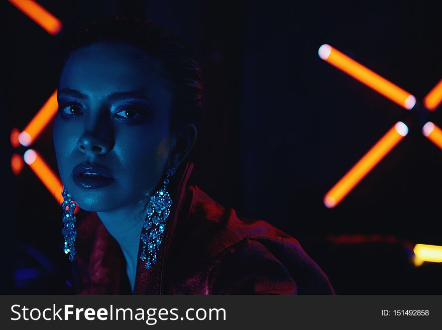 Cyberpunk close up of model wearing red bikers jacket sitting in leather sofa against neon