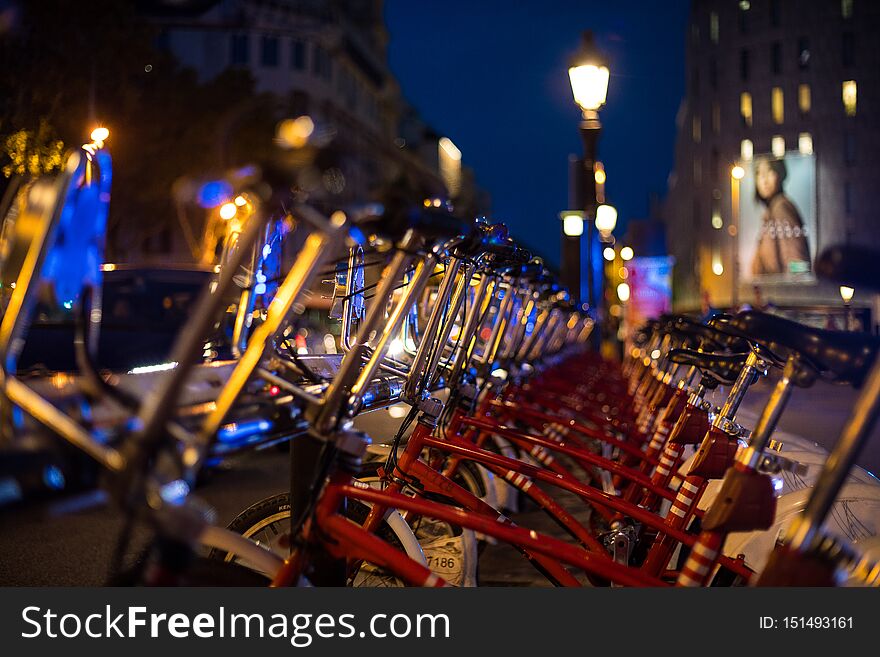 Red parked rental bikes at night perspective shot