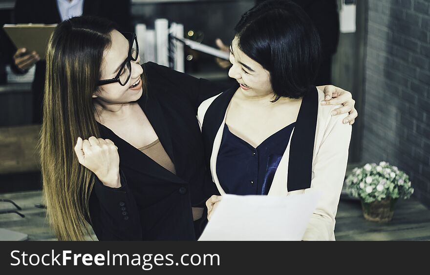 Two women happy and smiling happily with new job,with interview committee from Human Resources Department company standing behind