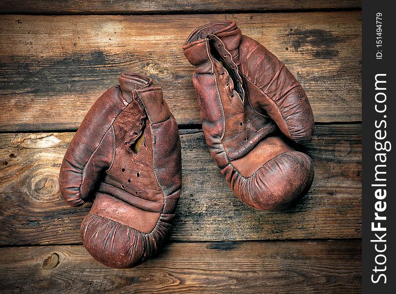 very old leather brown boxing gloves on a shabby wooden board