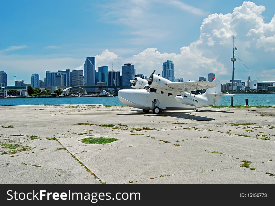 Old fashioned vintage seaplane used for charter flights to the Bahamas and the Caribbean tied down at its base at the port of miami with the downtown miami skyline in the distance.