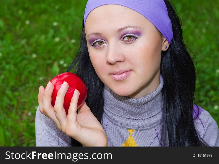 The young beautiful woman holds a red apple in a hand