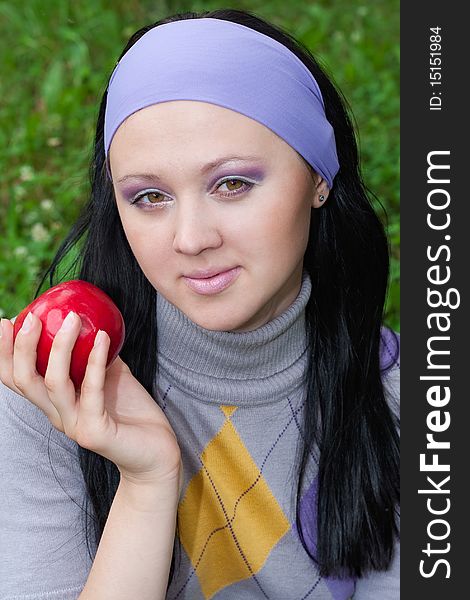 The young beautiful women holds a red apple in a hand. The young beautiful women holds a red apple in a hand