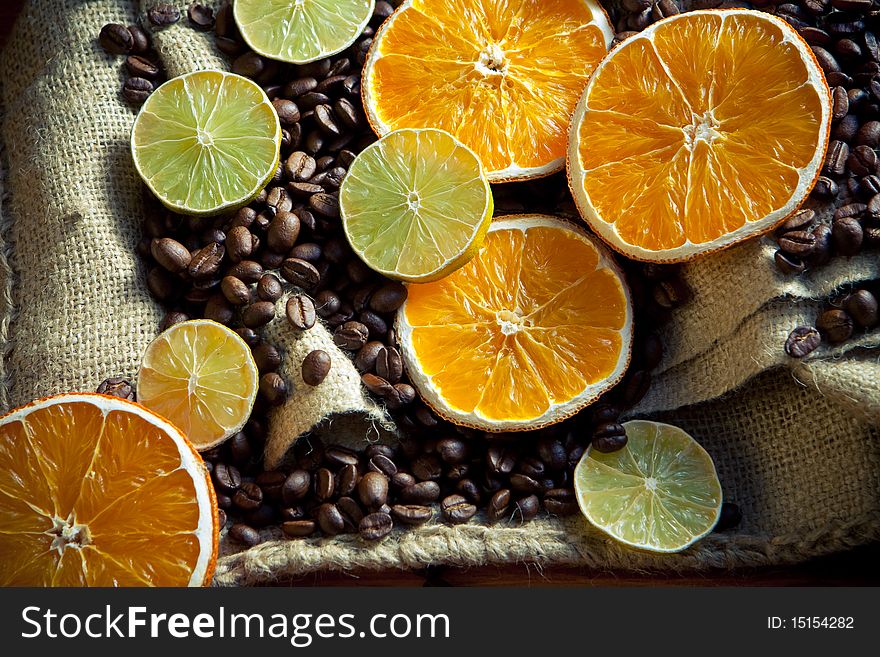 Coffee beans with orange and lemon on yuta material close-up