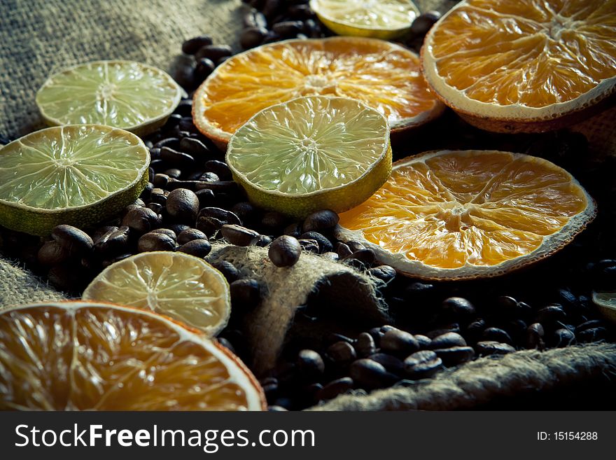 Coffee beans with orange and lemon on yuta material close-up