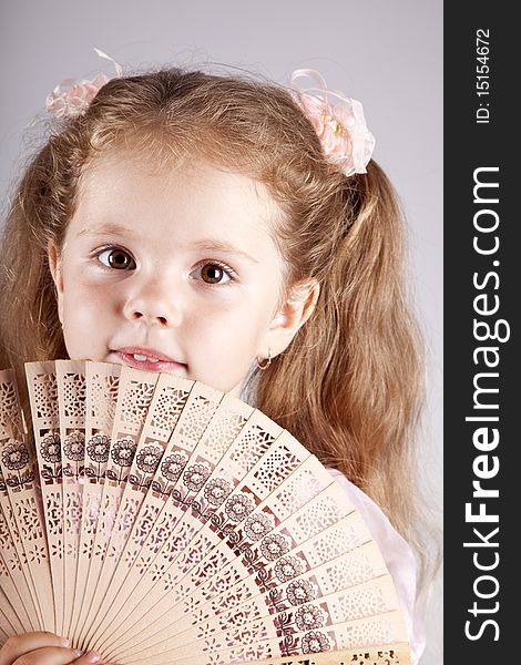 Portrait of beautiful young girl with fan. Studio shot.