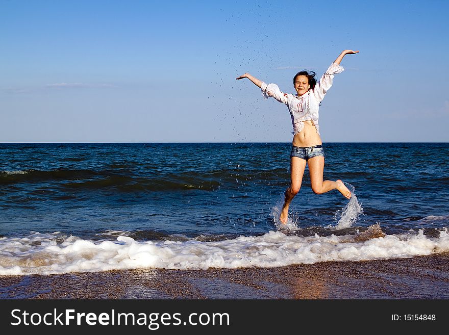 Happy girl in shorts and a white shirt on the sea. Happy girl in shorts and a white shirt on the sea