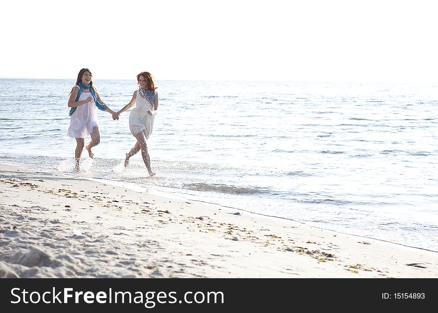 Two beautiful girls running on the beach. Outdoor photo.