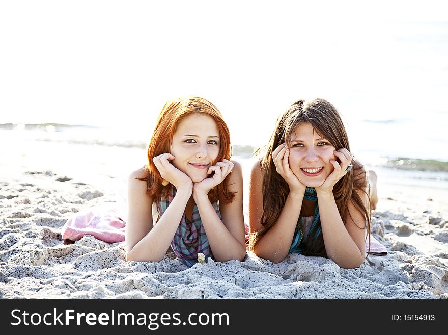 Two Beautiful Girls Lie On The Beach.