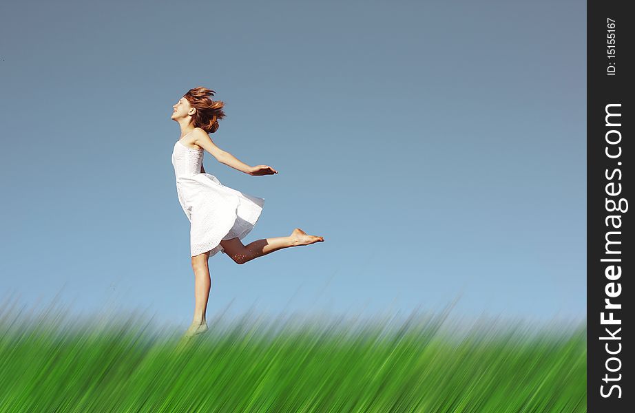 Young woman in white dress running on meadow with blurred grass