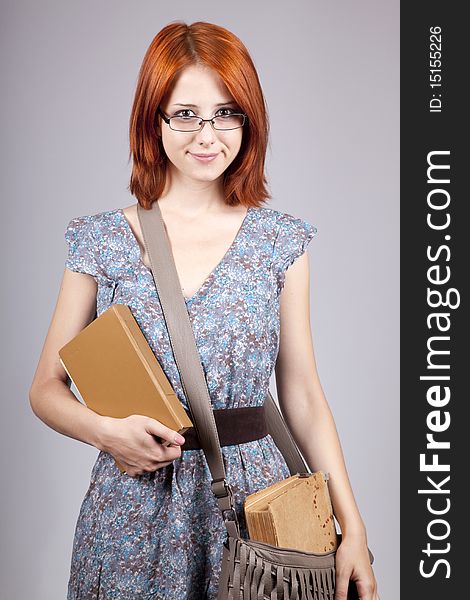 Red-haired girl keep book in hand. Studio shot.