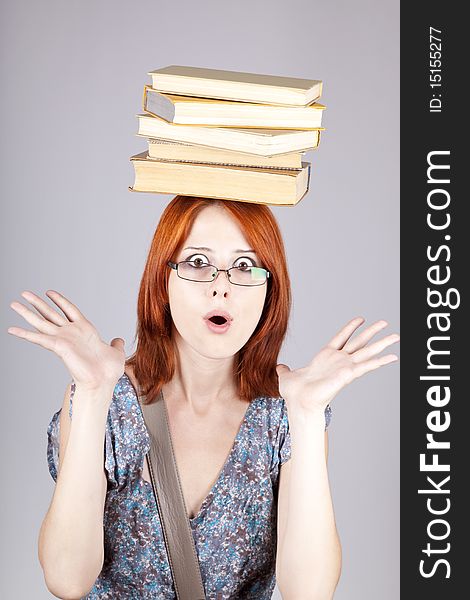 Red-haired girl keep books on her head. Studio shot.