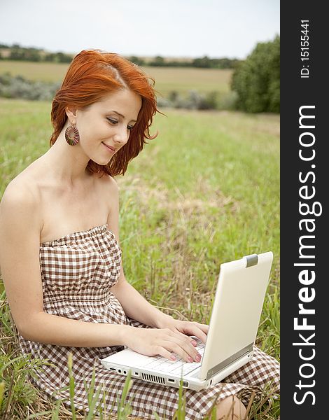 Young  fashion girl with noteboot at field. Outdoor shot.