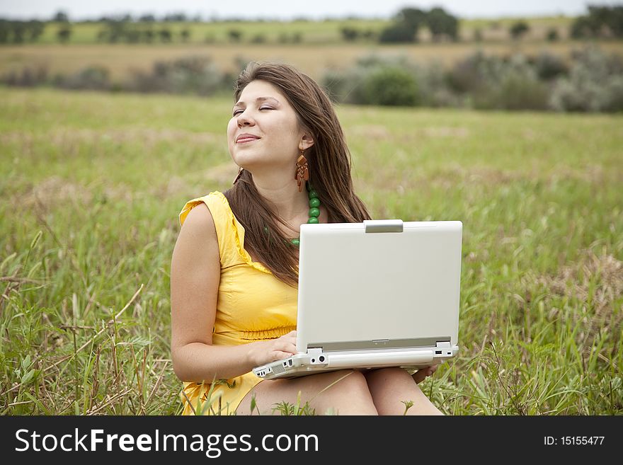 Young beautiful girl with notebook at field. Outdoor shot.