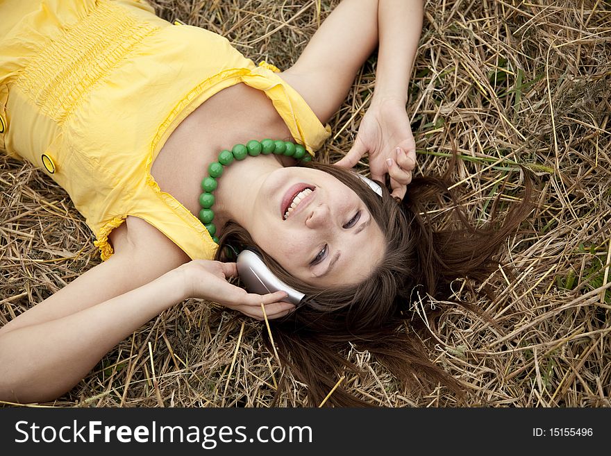 Young beautiful girl in yellow with headphones at field.